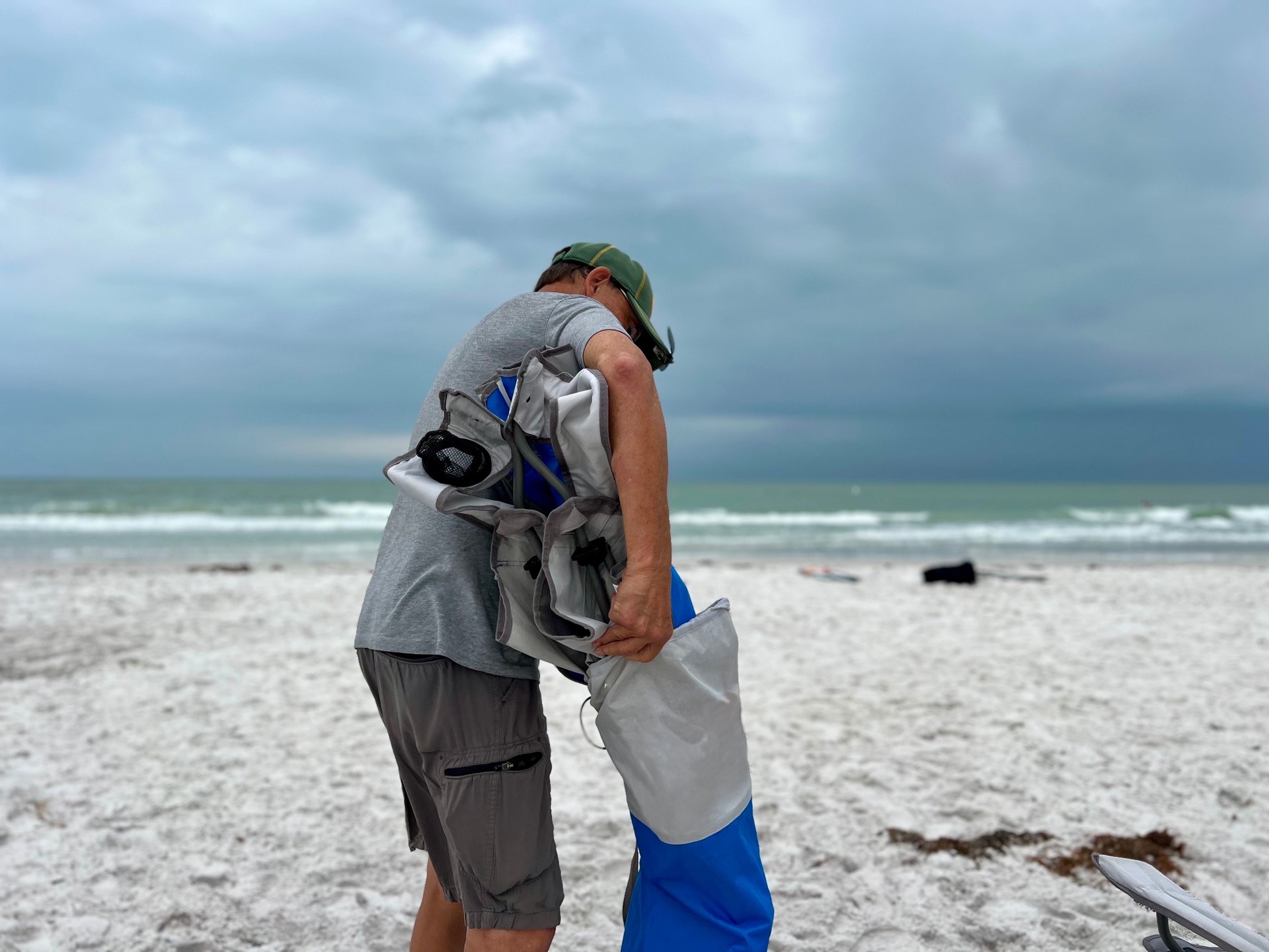 Storm coming with senior man almost done packing up on beach